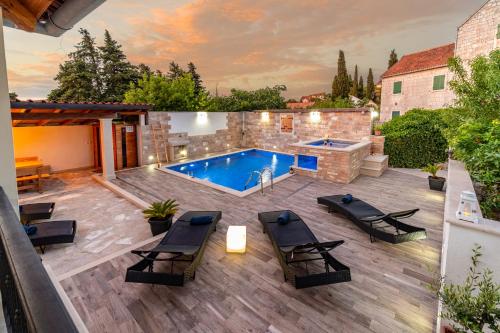 a backyard with a swimming pool and a patio with chairs at Luxury house David with heated pool, jacuzzi and sauna in Nerežišće