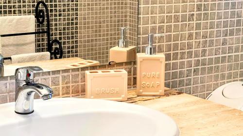 a bathroom with a sink and two soap dispensers on a counter at Casa da Japoneira in Horta