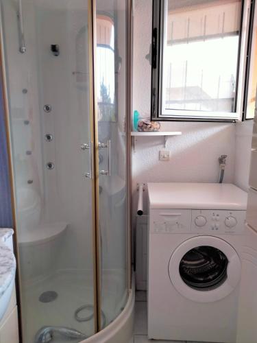 een kleine badkamer met een wasmachine en een douche bij Joli T2 résidence naturiste ULYSSE in Leucate