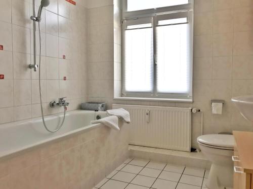 een badkamer met een bad, een toilet en een raam bij Haus Stothfang - Ferienwohnung 3 in Sassnitz
