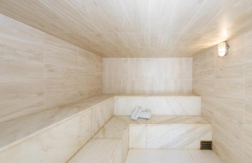 a sauna with white marble walls and a tub at Visual Praia Hotel in Natal