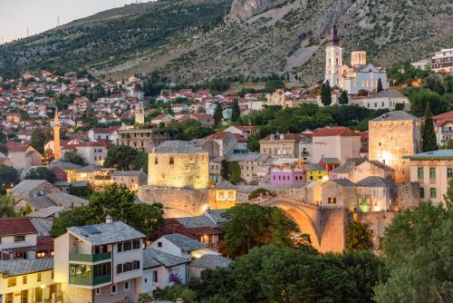 a cityscape of a town with a mountain in the background at Sky Penthouse Old Bridge with sauna and jacuzzi in Mostar