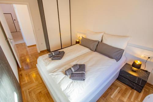 a large white bed with two towels on it at Sky Penthouse Old Bridge with sauna and jacuzzi in Mostar