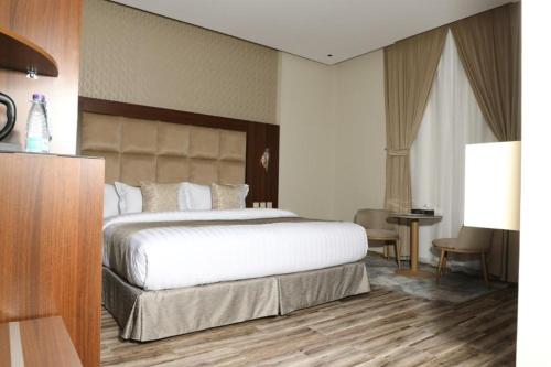 a bedroom with a large white bed and a table at فندق روند in Hafr Al Baten