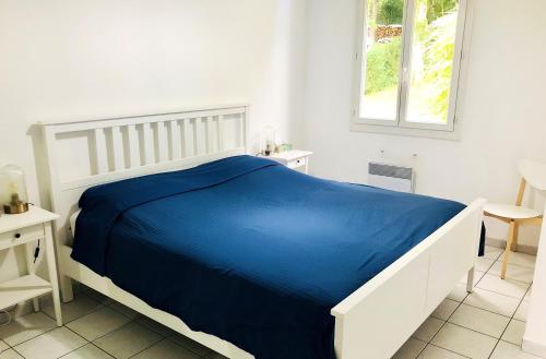 a white bedroom with a blue bed and a window at Villa de 4 chambres avec piscine privee sauna et jardin clos a Villemeux sur Eure in Villemeux-sur-Eure