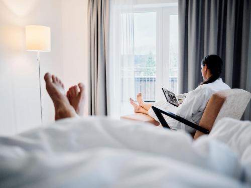 a woman sitting on a couch with her feet up on a window at ARX Guesthouse in Schladming