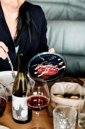 a woman sitting at a table with a bottle of wine at ARX Guesthouse in Schladming