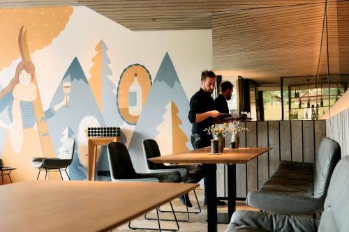 Due uomini seduti ai tavoli in un ristorante con un murale di ARX Guesthouse a Schladming