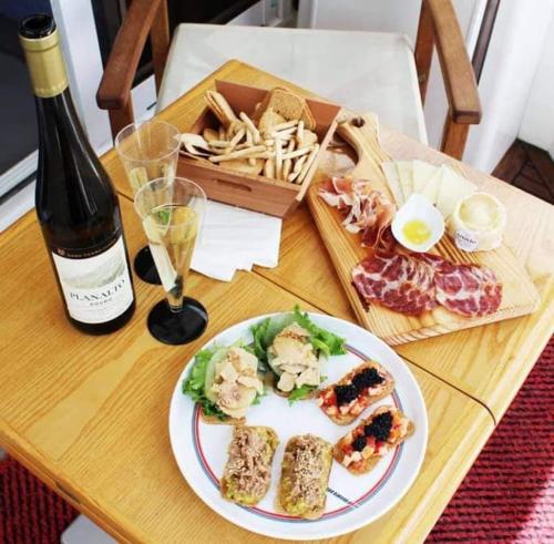 a table with a plate of food and a bottle of wine at Barco Apartamento Buzios III Cascais in Cascais