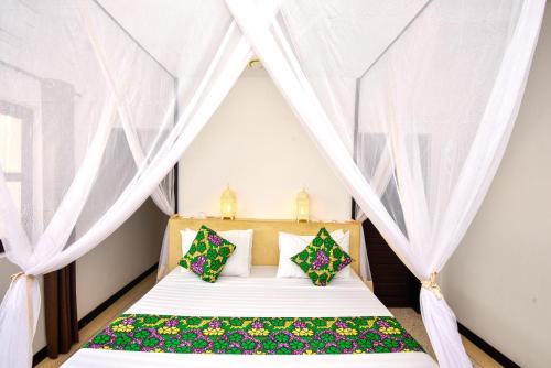 a bedroom with a bed with white curtains at Daima Villas in Jambiani