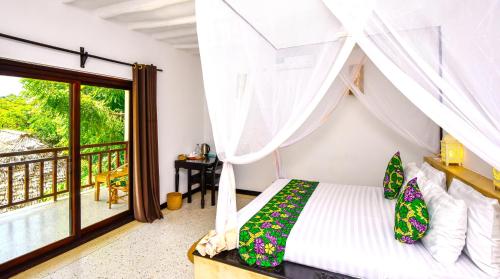 a bedroom with a bed and a balcony at Daima Villas in Jambiani