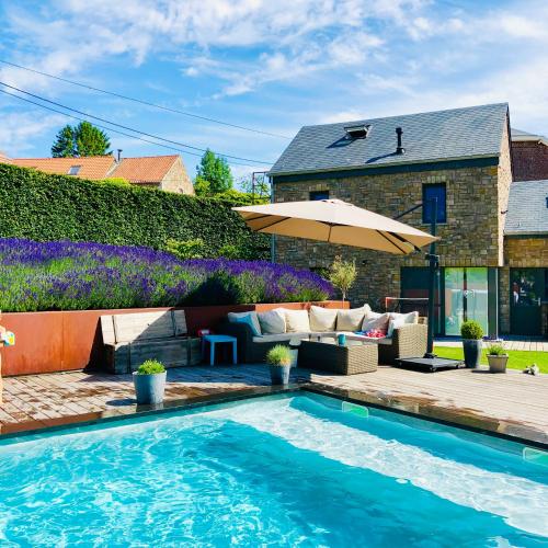 WanzeにあるJuste à Côté, Maison de caractère avec piscineのスイミングプールと傘付きの家