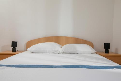 a bed with white sheets and two pillows at Apartman Ana Borić in Podgora