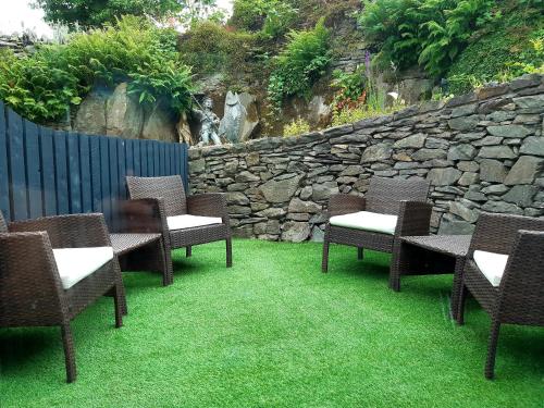a group of chairs and tables on grass next to a stone wall at No's 7 and 8 Llewelyn Apartments in Llanberis