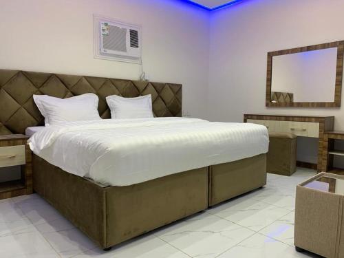 a bedroom with a large bed with a mirror at أجنحة عبدالعزيز للوحدات السكنية in Sulţānah