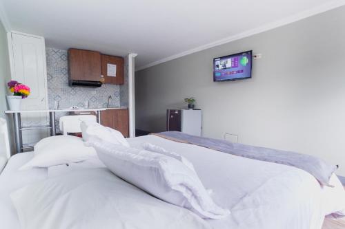 a bedroom with a white bed with a tv on the wall at ApartaSuites & Hotel Bogota Suamox in Bogotá