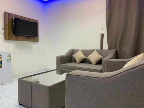 a living room with a couch and a tv at أجنحة عبدالعزيز للوحدات السكنية in Sulţānah