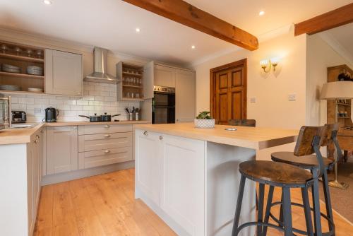 a kitchen with white cabinets and a bar with stools at Bridge Hotel Brandon in Brandon