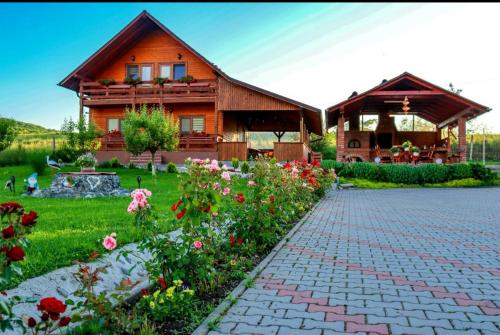ein Holzhaus mit einer Ziegelsteinfahrt und Blumen in der Unterkunft Cabana LaGică in Beclean