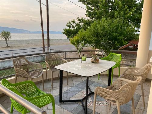 einen Tisch und Stühle auf einem Balkon mit Blick auf den Strand in der Unterkunft Atelié Yiouli in Pefki