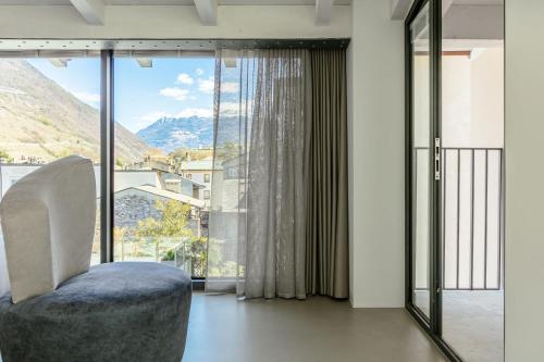 a living room with a chair and a large window at DOMUS CAVOUR Rooms&Suites in Tirano