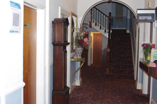 a hallway with stairs and a vase on a table at Eastmount Hall Hotel in Shanklin