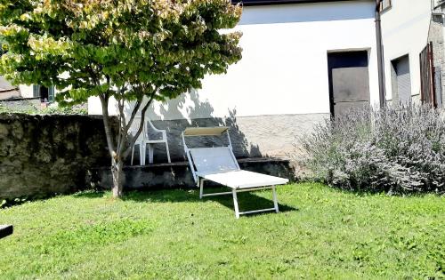 a chair sitting in the grass next to a tree at Casa Vacanza l' antico molino in Grosotto