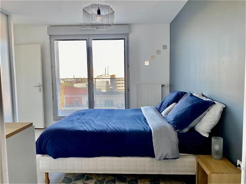 ein Schlafzimmer mit einem blauen Bett und einem Fenster in der Unterkunft Charmant T2 lumineux au pied de la gare in Courcouronnes