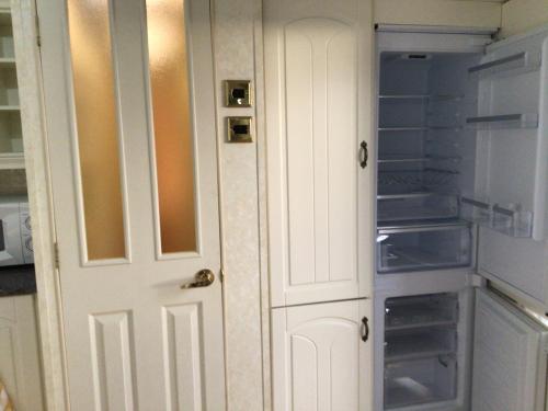 a white door in a kitchen with an empty refrigerator at Beautiful 2-Bed holiday home nr Kynance cove in Helston