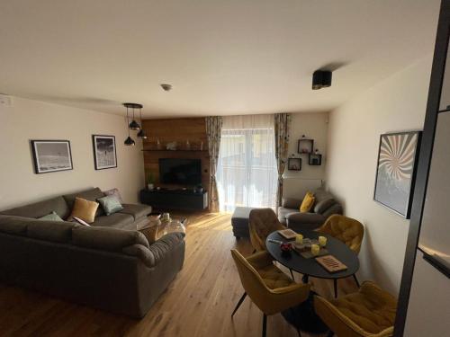 a living room with a couch and a table at Luxusní apartmán GRAND v centru Harrachova se saunou, wallboxem EV, parkováním zdarma, Netflix a HBO, velkým balkonem a výhledem na Čertovu horu ,sjezdovku a skokanské můstky in Harrachov