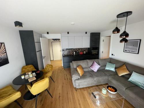 a living room with a couch and a table at Luxusní apartmán GRAND v centru Harrachova se saunou, wallboxem EV, parkováním zdarma, Netflix a HBO, velkým balkonem a výhledem na Čertovu horu ,sjezdovku a skokanské můstky in Harrachov