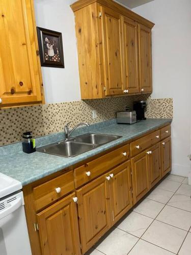una cocina con armarios de madera y fregadero en My Cozy Apartment Cottage, en Grande-Digue