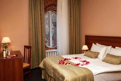 una habitación de hotel con una cama con flores rojas. en Arkada Hotel, en San Petersburgo