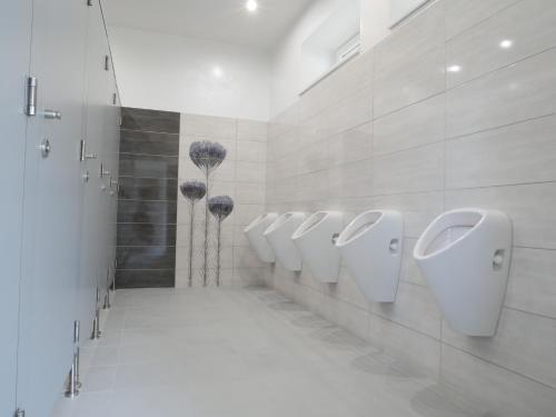 a bathroom with four urinals and a row of sinks at Camping Rožnov in Rožnov pod Radhoštěm