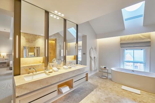 a bathroom with two sinks and a tub and a large mirror at COMO The Treasury in Perth