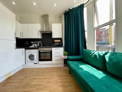 un salon avec un canapé vert dans une cuisine dans l'établissement 1 Bed 2 Person Apartment City Centre, à Cardiff