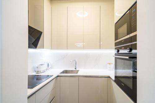 a white kitchen with a sink and a microwave at Apartments Zadro in Dubrovnik