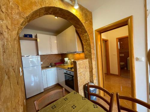 a kitchen with a white refrigerator and a table with chairs at Apartments Jakasa in Trogir