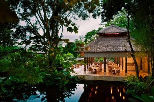 a pavilion with tables and chairs next to a pond at COMO Uma Ubud in Ubud