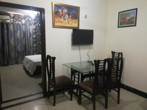 um quarto com uma mesa e cadeiras e uma televisão em Lovely 1-Bedroom Apartment em Lahore