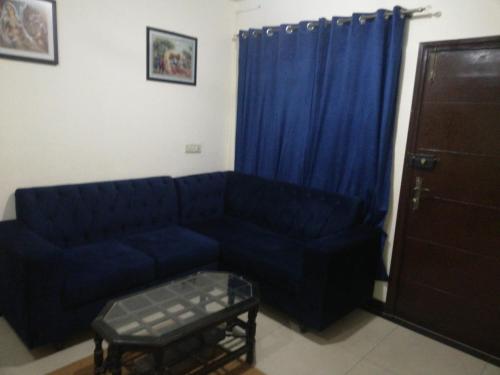 uma sala de estar com um sofá azul e cortinas azuis em Lovely 1-Bedroom Apartment em Lahore