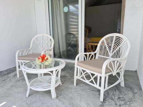 three white chairs and a table on a porch at Le Recif Hotel Rodrigues in Rodrigues Island