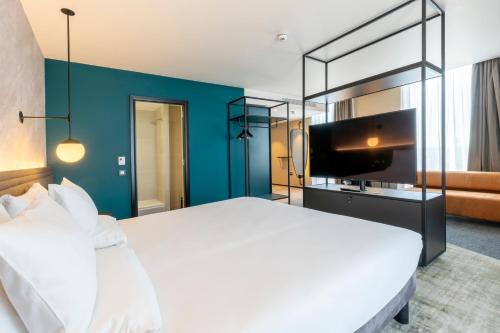 a bedroom with a large white bed and a blue wall at Novotel Liverpool Paddington Village in Liverpool