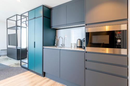 a kitchen with blue cabinets and a microwave at Novotel Liverpool Paddington Village in Liverpool