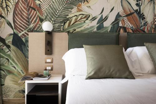 1 dormitorio con 1 cama con papel pintado de plantas en Life Hotel, en Bibione