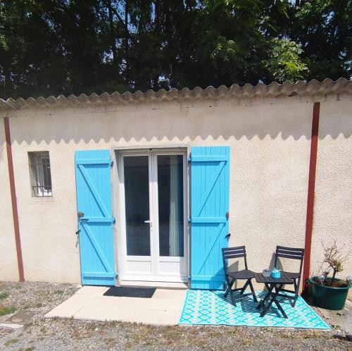 une maison avec des portes bleues, une table et deux chaises dans l'établissement Studio indépendant au calme avec parking privatif, à Caucalières