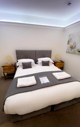 a bedroom with a large white bed with two tables at Tides Reach Guest House in The Mumbles