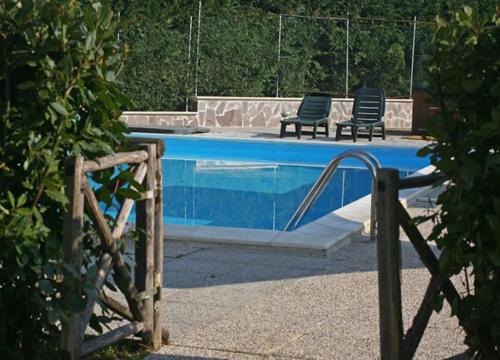 a swimming pool with two chairs sitting next to it at Hotel Residence I Briganti di Capalbio in Capalbio