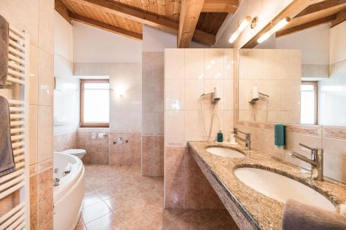 een badkamer met 2 wastafels, een bad en een toilet bij Hotel Weingarten in Appiano sulla Strada del Vino