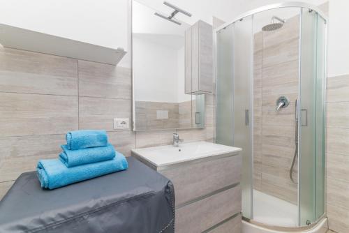 a bathroom with a sink and a shower with blue towels at Quercus Ilex B in Arzachena